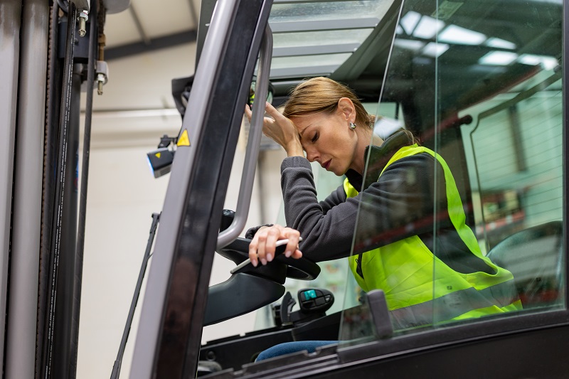 Female warehouse worker driving forklift. Warehouse worker preparing products for shipmennt, delivery, checking stock in warehouse.